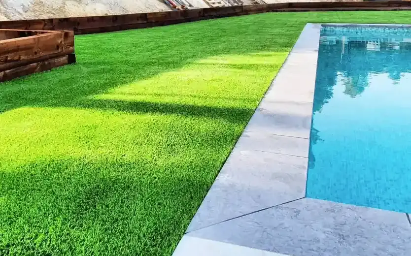 Césped artificial junto al borde de una piscina en un jardín